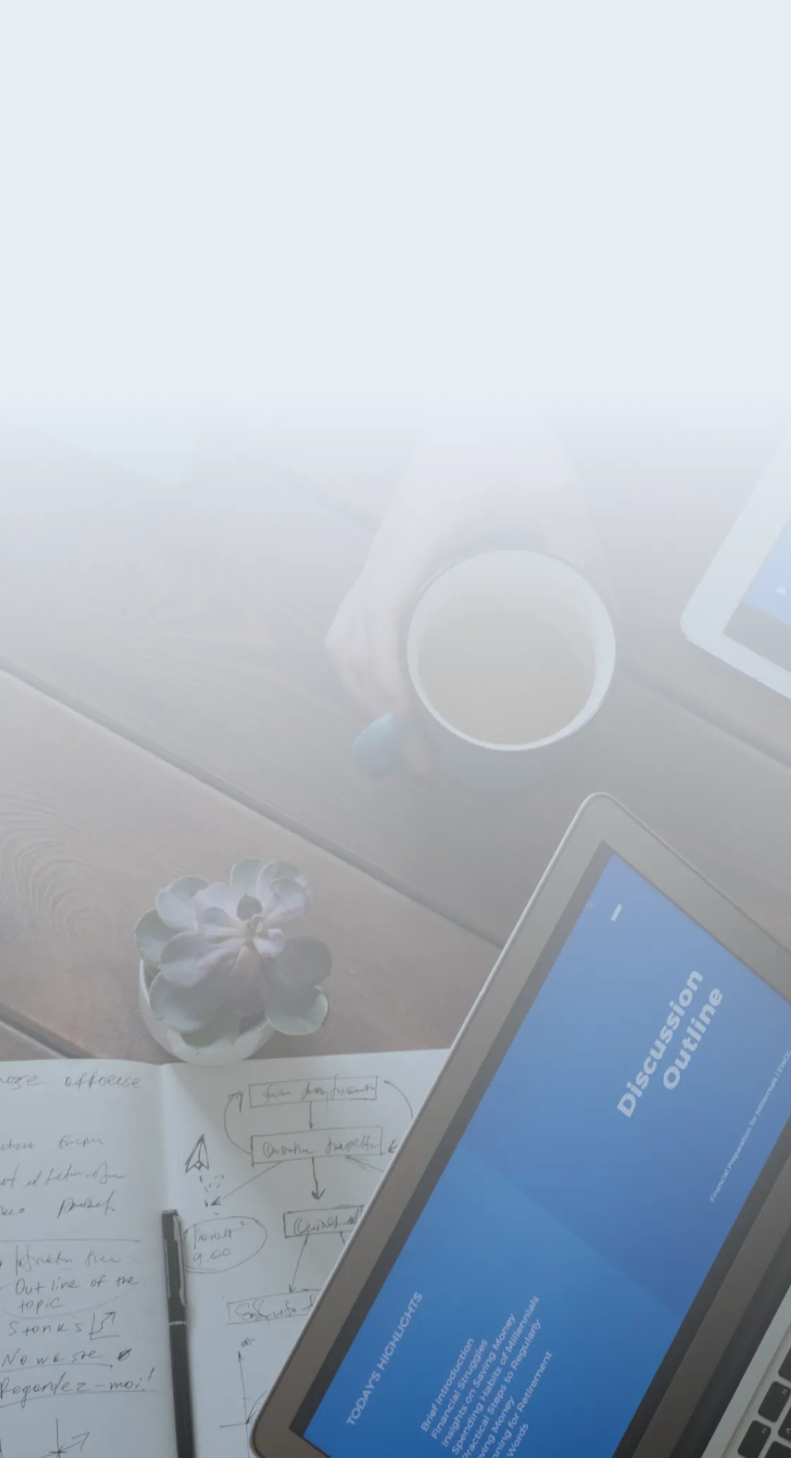 Business meeting with tablets and a laptop displaying presentation slides, along with notebooks and coffee on a wooden table.