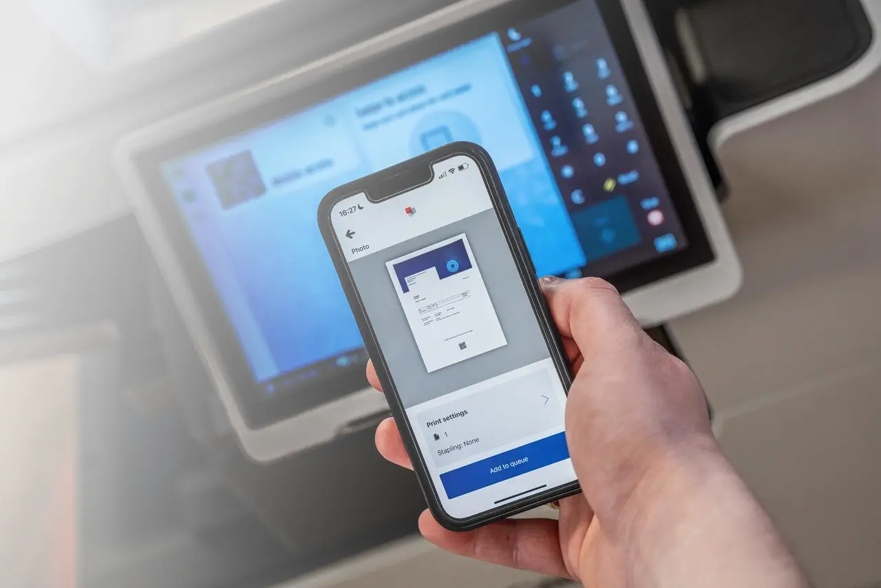 Person holding a phone with the screen showing a print preview before printing.