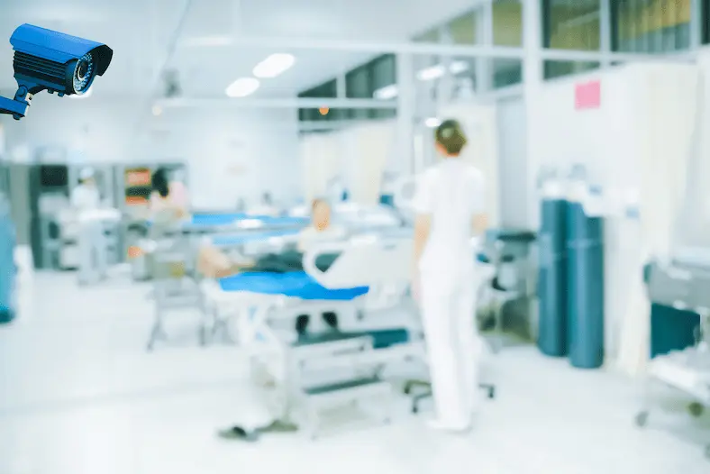 A security camera is monitoring a hospital room with medical staff and patients inside.
