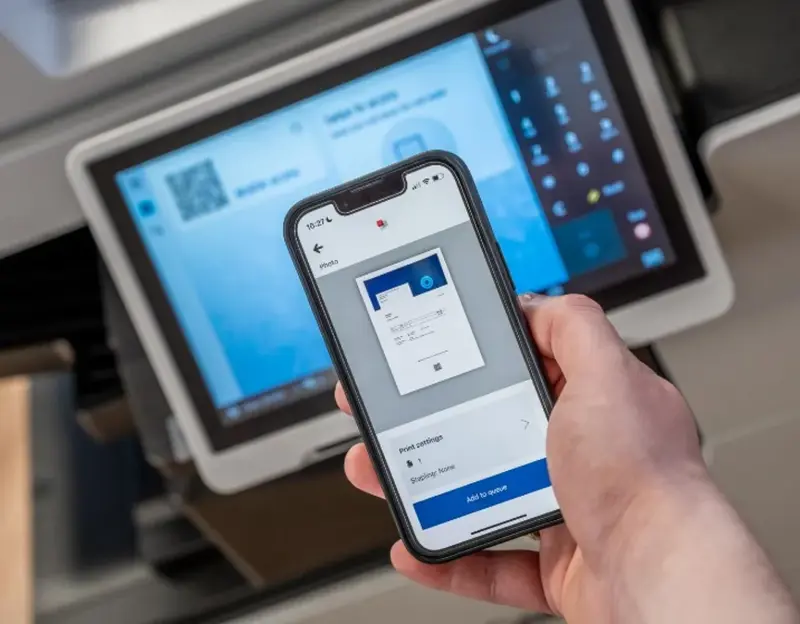 Person holding a phone with the screen showing a print preview before printing.