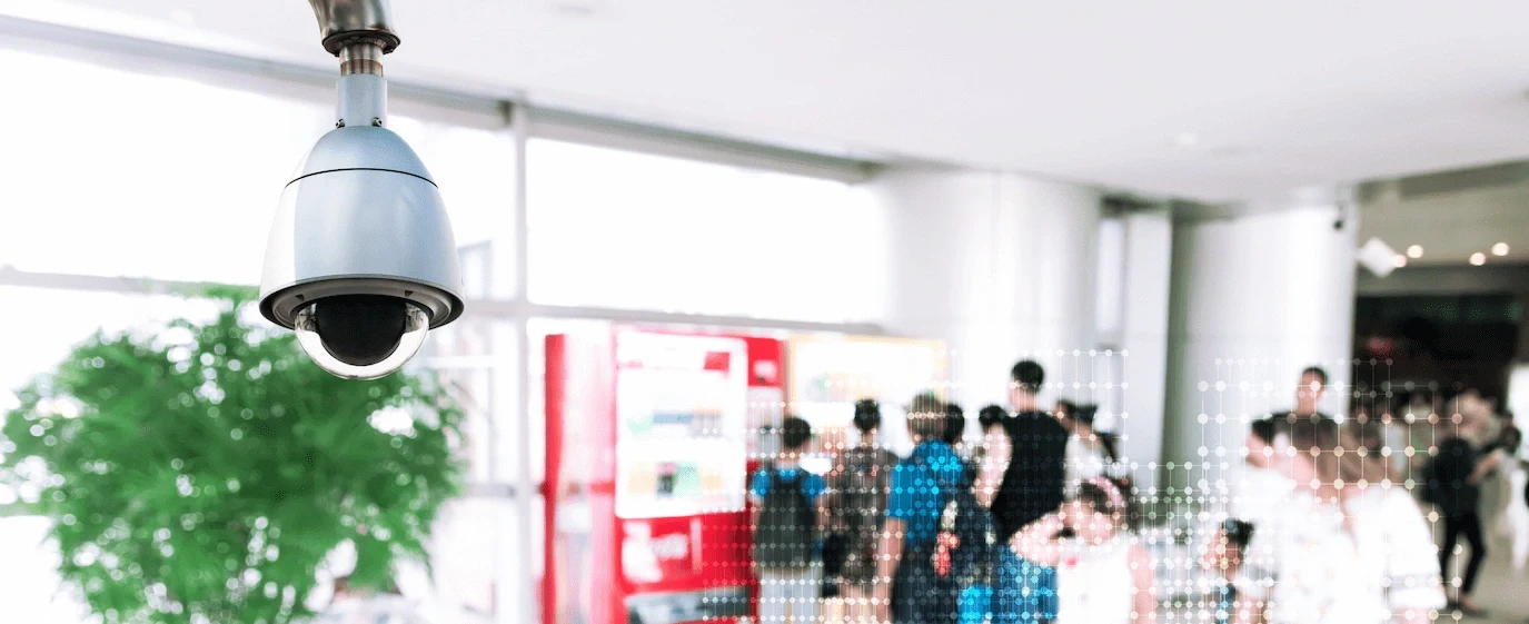 A security camera monitors people moving through a busy public indoor space.